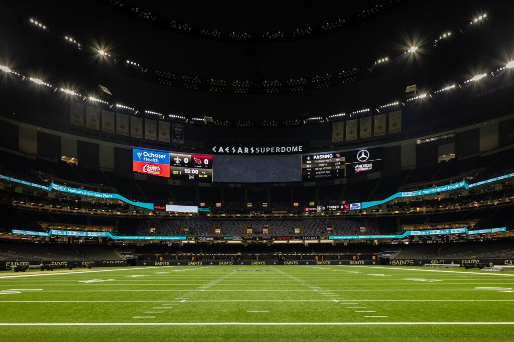 New Orleans Superdome - Interior view of a large domed stadium with field lighting, scoreboard, and seating under a dark dome ceiling