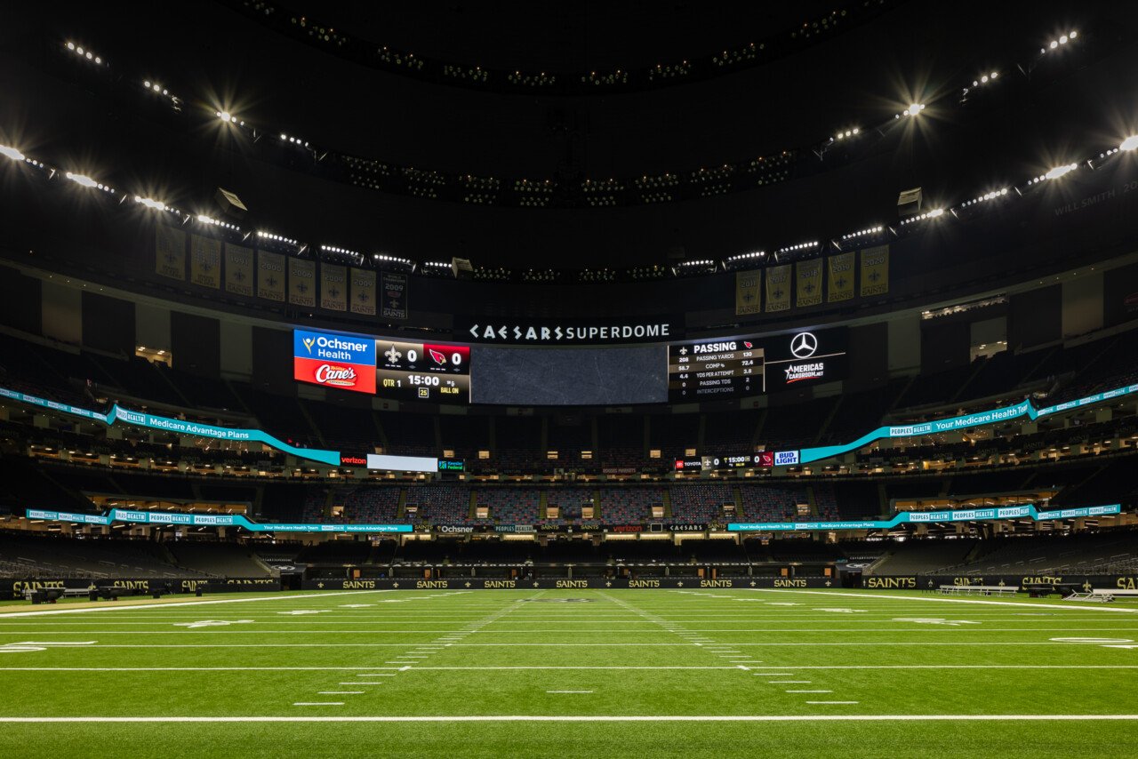 New Orleans Superdome - Interior view of a large domed stadium with field lighting, scoreboard, and seating under a dark dome ceiling